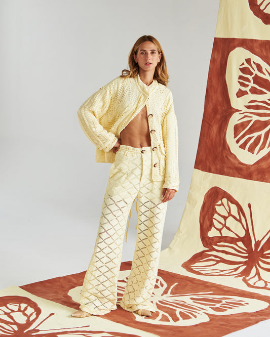 Chaqueta artesanal tejida a mano en tono arena, con detalles calados que la hacen ligera y sofisticada. Botones naturales y un corte relajado para un look fresco, cómodo y elegante. Perfecta para un estilo mediterráneo chic que te acompaña del día a la noche.&nbsp;
