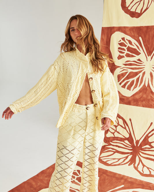 Chaqueta artesanal tejida a mano en tono arena, con detalles calados que la hacen ligera y sofisticada. Botones naturales y un corte relajado para un look fresco, cómodo y elegante. Perfecta para un estilo mediterráneo chic que te acompaña del día a la noche.&nbsp;